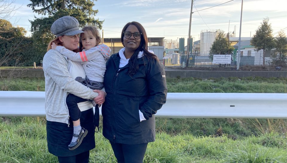 Laurie (left), a West Eugene neighbor, holds her daughter, Savannah in her arms. Standing beside them is Arjorie Arberry-Baribeault, the West Eugene Community Organizer for Beyond Toxics and Laurie's friend.