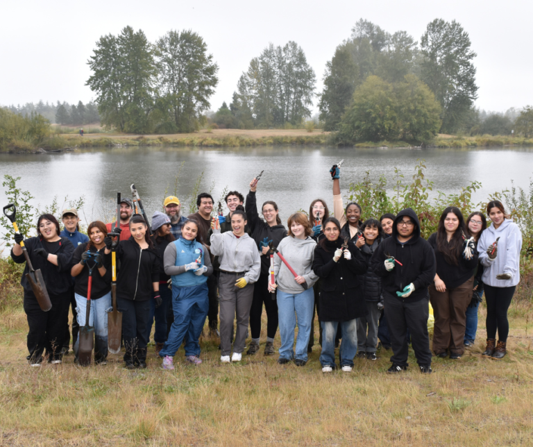 A large group of volunteers in front of a pond on an overcast day.