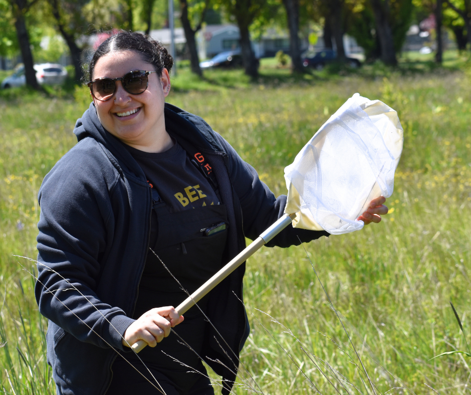 A volunteer smiles with a bee net in her hands.